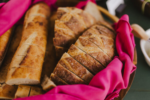 Sliced bread loaves are arranged on a tray, partially wrapped in a bright pink cloth, creating an inviting display reminiscent of Maui personal chef culinary finesse.